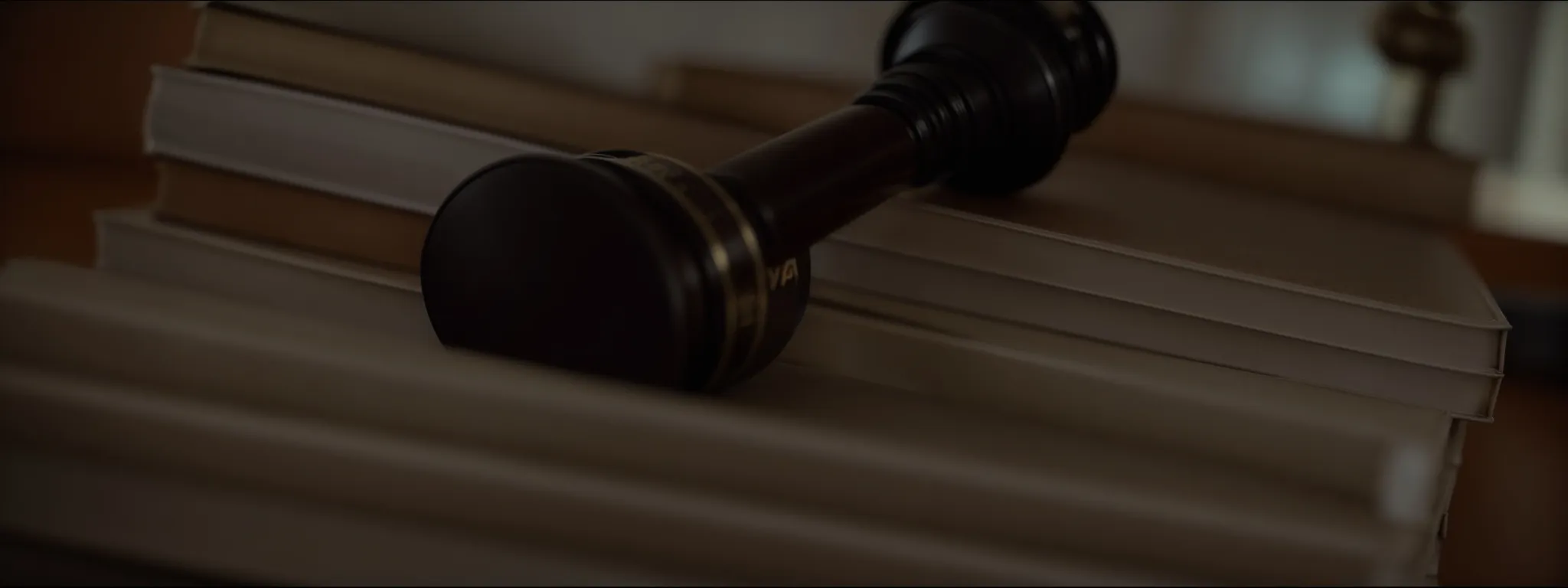 a gavel lying atop a collection of thick law books, with a globe in the background.
