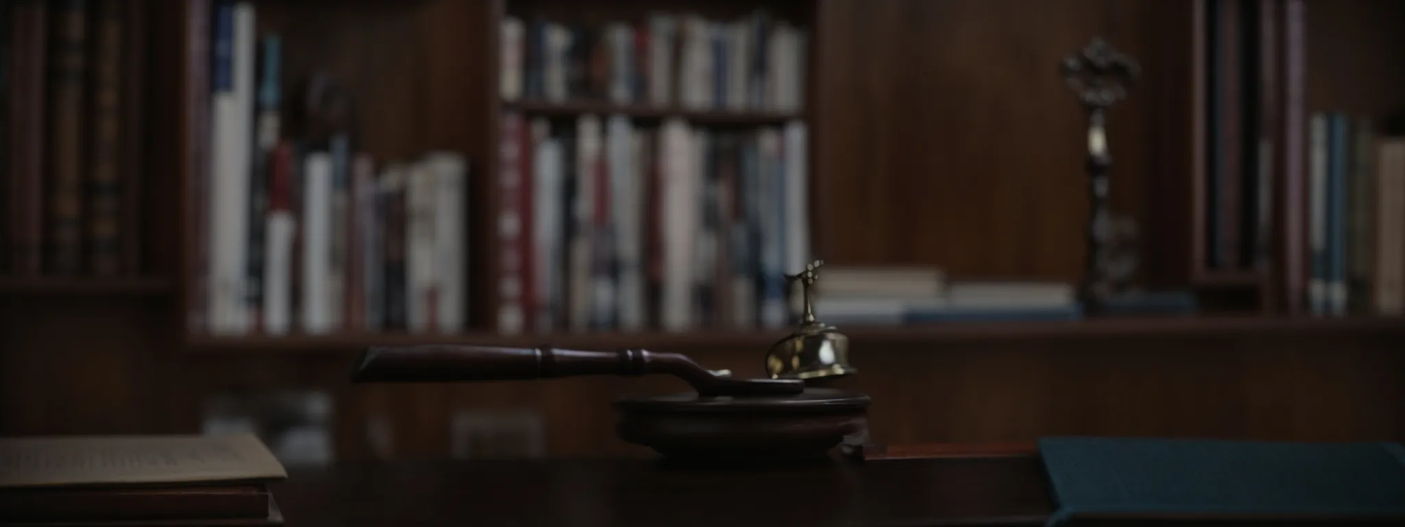 a gavel and a balance scale placed on a table against a background of law books.