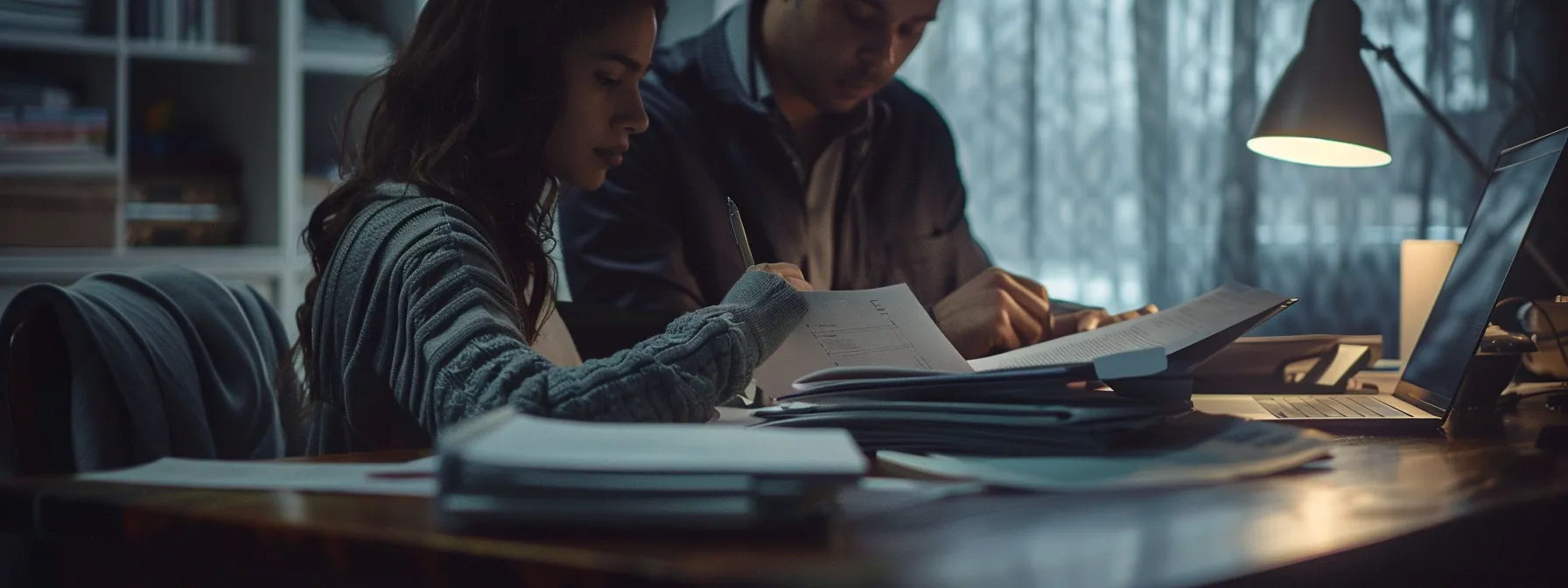 a close-up of two individuals carefully reviewing a purchase assignation agreement, with a stack of legal documents and a laptop open on a desk, showcasing diligence and focus on mitigating risks.