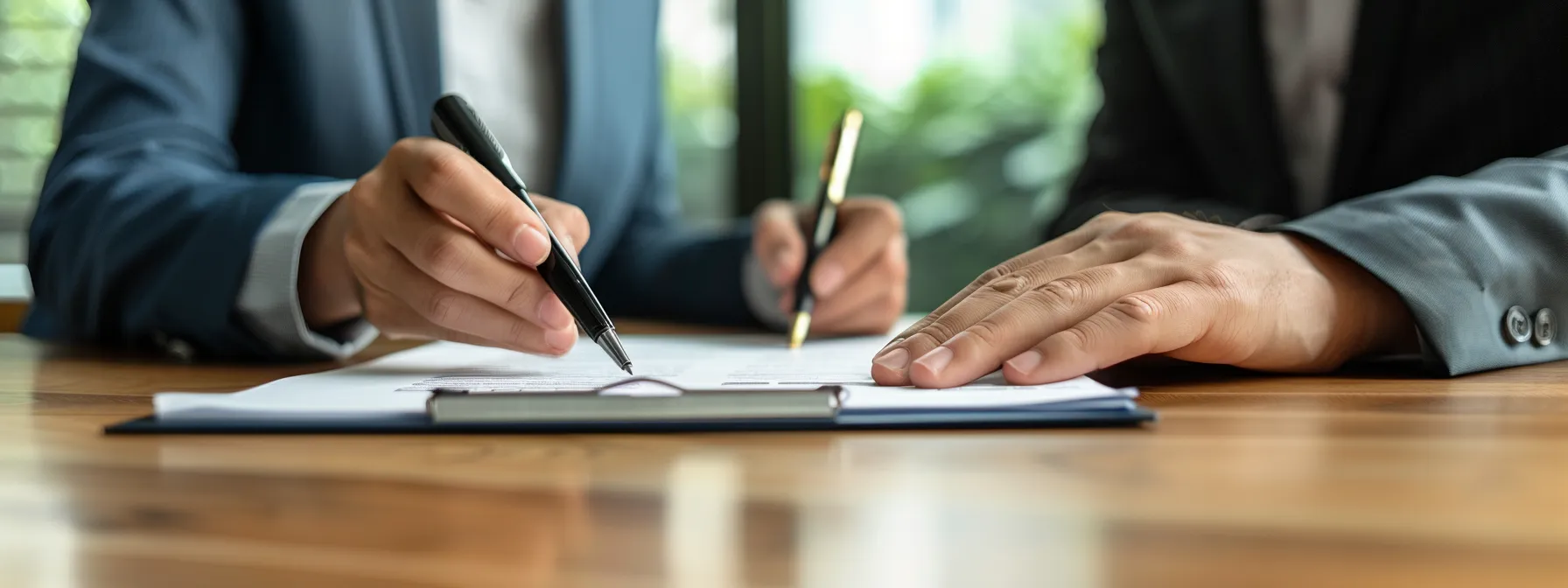 a group of professionals signing a written agreement in a well-lit boardroom, with legal documents and pens neatly arranged on a polished conference table.